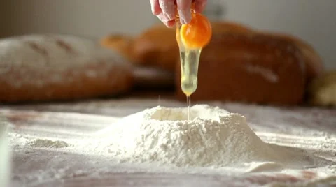 Baker adding egg to flour on table, slow motion Stock Footage 10735261