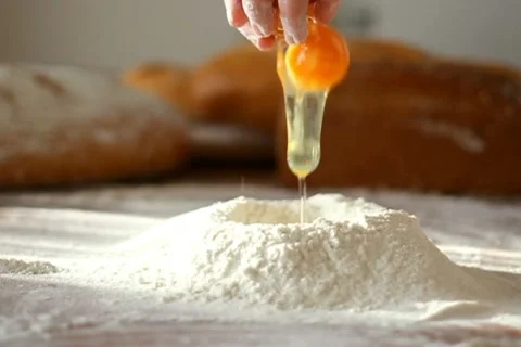 Baker adding egg to flour on table, slow motion Video stock 10735262