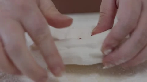 A baker adds drops of pink food colouring to fondant and hand kneads and mixes Stock Footage 319829458
