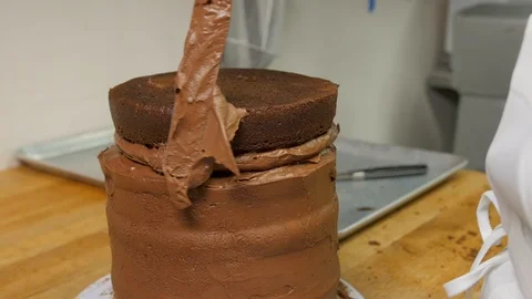 Baker adds final layer to tiered chocolate cake Stock-Footage 94251354