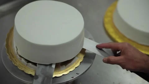 A baker adds a second layer to a wedding cake Stock Footage 231414556