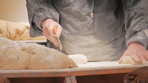 Baker in apron working with big dough piece. Commercial bakary. Stockbeeldmateriaal 98519825