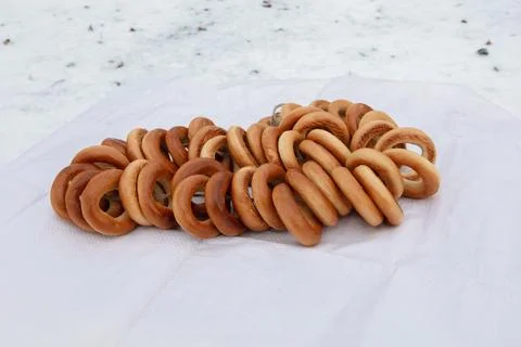 Baker arranges ring-shaped bread on white cloth outside in daylight for dis.. Stock Photos