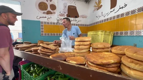 A baker arranges stacks of round flatbreads at a colorful market stall while Stock Footage 340823641