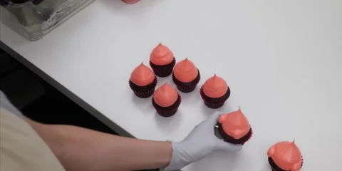 Baker Arranging Fresh Cupcakes with Pink Frosting on White Table Stock Footage 343588848
