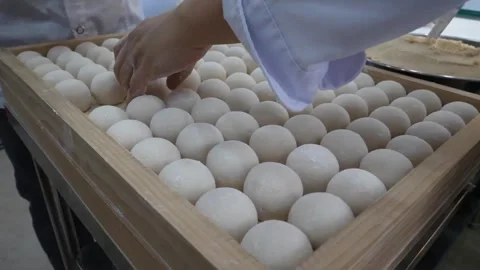 Baker arranging rows of fresh white dough balls in a wooden tray Stock Footage 345291941