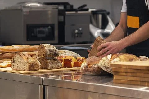 Baker in bakery cutting fresh bread. Food Stock Photos