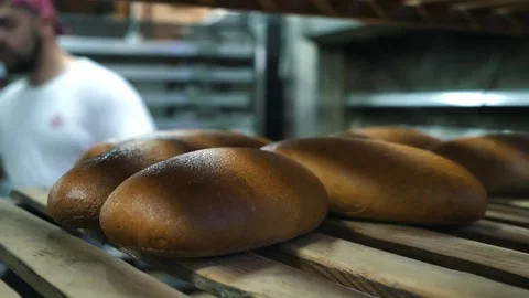 A baker bakes fresh bread. Bearded mature baker taking out freshly baked loaves Stock Footage 274345652