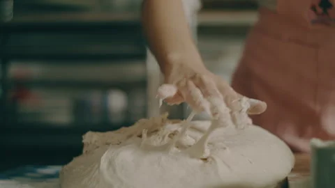 Baker begins to spread dough over counter top Stock Footage 274650785