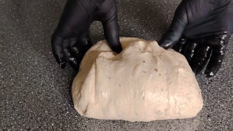Baker with black gloves kneading and folding sourdough bread dough. Stock Footage 333756721