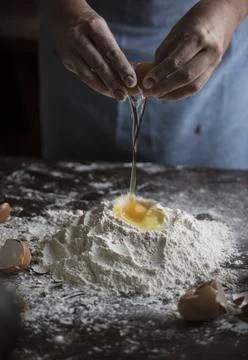 Baker breaking an egg into a flour mixture Stock Photos