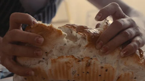 Baker breaking off a piece of piping hot freshly baked bread Stock Footage 274680797