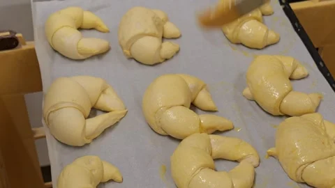 Baker Brushing Egg Wash on Raw Croissants Video stock 336395091