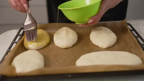 Baker brushing raw dough with egg wash before baking. Close up of homemade buns Stock Footage 329800800