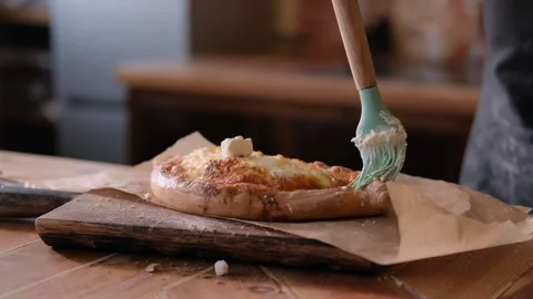 Baker buttering freshly baked pie on a wooden board at home in the kitchen Video stock 267012539