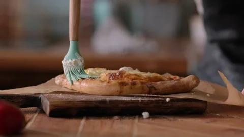 Baker buttering freshly baked pie on a wooden board at home in the kitchen Stock Footage 267012592