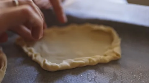 Baker carefully crimping edges of pie crust on baking sheet Stock Footage 305046197