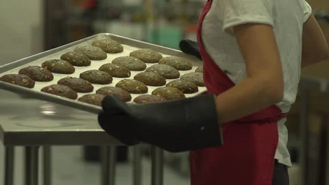 Baker carries cookie sheet full of baked cookies in slow motion Stock Footage 128461610