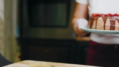 Baker carrying a decorated chocolate cake toward the table, 4K Stock Footage 341121180