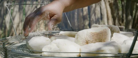 Baker checking on buns cooking on an open fire stove Stock Footage 106218803
