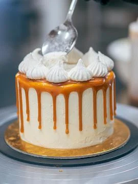 Baker chef decorating cup cakes with cream and salty caramel using black glov Stock Photos