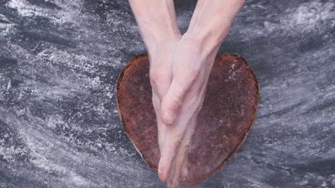 Baker clap hands above rye sourdough artisan bread in shape of heart Stockbeeldmateriaal 130495284