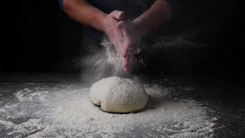 Baker clapping his hands filled with flour and flours fly. Dough on the table Stock Footage 258585254