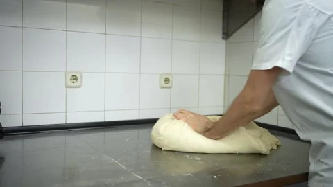 Baker cleaning his hands and manually kneading bread dough before cutting it 스톡 동영상 251368349