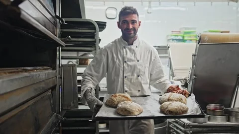 Baker cook tasty warm bread loaf at bakery. Smiling man portrait. Bake fresh bun Stock Footage 271222904