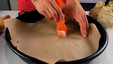 Baker cooking applying butter to baking paper in cake pan using silicone brush. Stock Footage 313045952