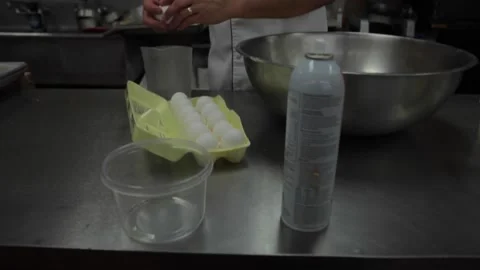 Baker cracks eggs in bakery Stock Footage 231414984