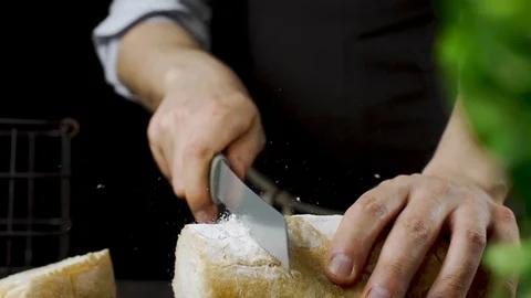 Baker cuts bread in the kitchen in slow motion 動画素材 104972748