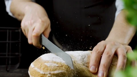 Baker cuts bread in the kitchen in slow motion Stock Footage 104972897