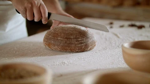 Baker cuts bread with knife in traditional bakery Stock Footage 93099294