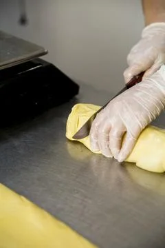 Baker cuts dough on a work table in a kitchen during the day 库存照片