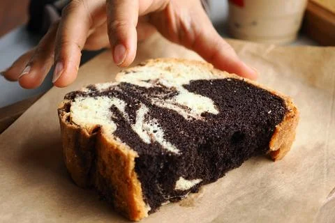 Baker cuts a slice of marbled chocolate cake in a cafe Stock Photos