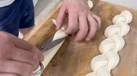 Baker cutting bread dough to create loaf of bread in his small bakery. Stock Photos