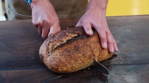 Baker Cutting a Loaf of Sourdough Bread in Half Stock Footage 245137361