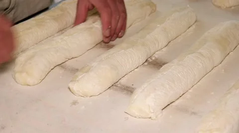 Baker cutting the raw dough. Manufacturing process of long loaf bread Stock Footage 64470662