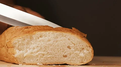 Baker is cutting slice of his freshly baked bread with kitchen knife on a woo Stock Footage 65003167