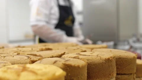 Baker cutting the top of cake with a serrated leveler cake. Making a layer cake. Stock Footage