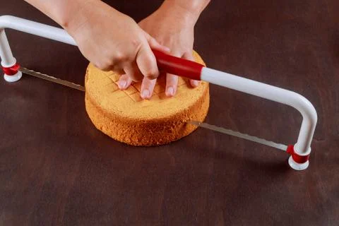 Baker cutting the top of cake with a serrated leveler cake. Stock Photos