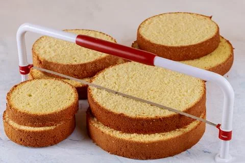 Baker cutting the top of cake with a serrated leveler cake. Stock Photos