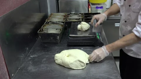 Baker is cutting, weighing, and putting the dough into a rectangle loaf pans Stock Footage 251786169