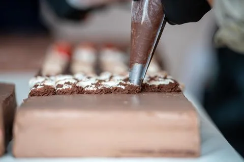 A baker decorates a chocolate cake. Background with selective focus and copy  Stock Photos
