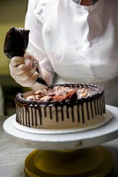 Baker decorates chocolate cake in kitchen setting 库存照片
