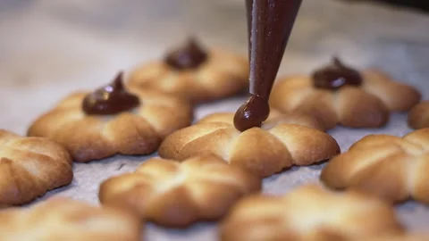 Baker decorates freshly baked cookies with chocolate icing in kitchen Vídeos de archivo 346083992