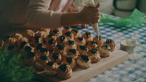 Baker decorates pastries with white and black topping Stock Footage 274649954