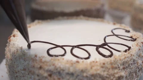 A baker decorating the cake with chocolate dressing at the bakery Stock Footage 164401691