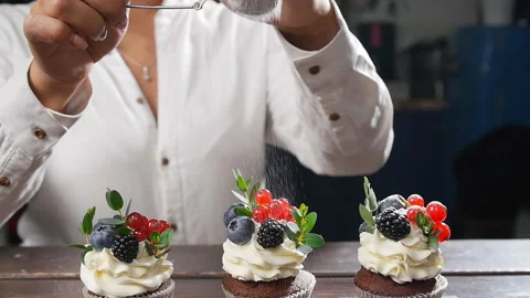 Baker decorating tasty cupcake. Icing sugar sprinkled on cake Stock Footage 95938260